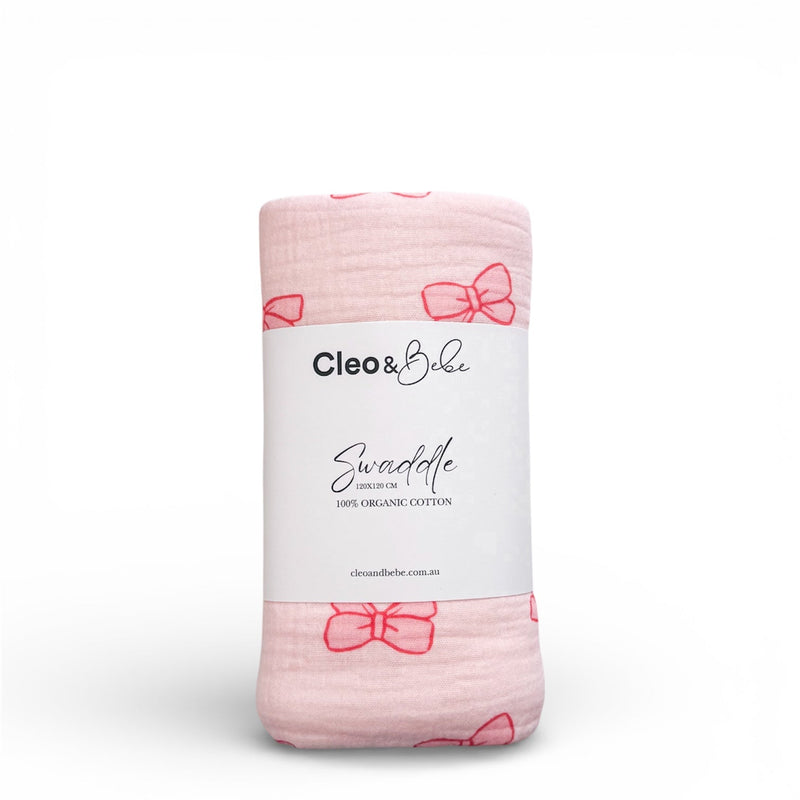 Pink swaddle blanket with bow patterns and 'Cleo & Belle' label on a white background